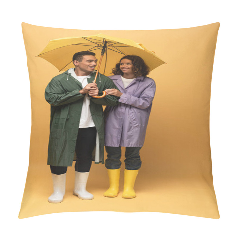 Personality  Smiling Interracial Couple In Raincoats And Rubber Boots Holding Umbrella On Yellow Background Pillow Covers