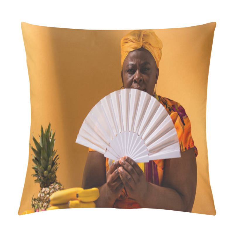 Personality  Serious Middle Aged African American Woman Sitting Near Fruits And Holding Fan On Orange Pillow Covers