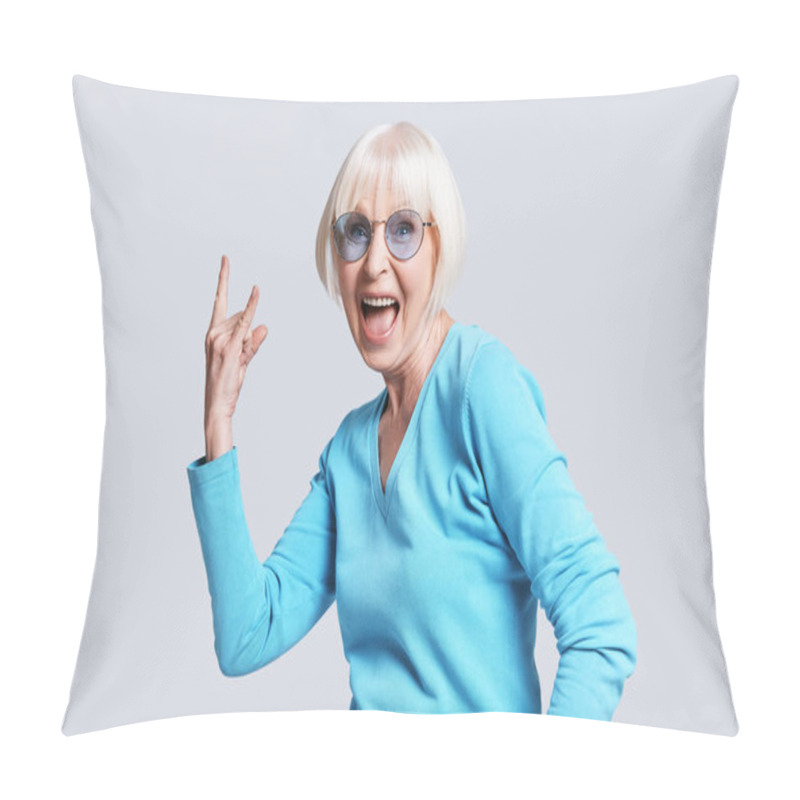 Personality  Cool Senior Woman With Short Grey Hair Posing At Grey Background In Studio, Wearing Stylish Glasses And Gesturing Rock Sign With Hand Pillow Covers