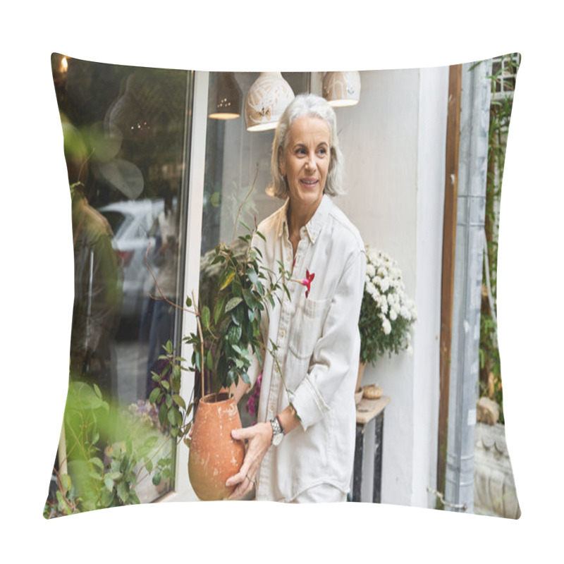 Personality  A Joyful Woman With Silver Hair Carries A Potted Plant, Smiling In A Garden Shops Outdoor Space. Pillow Covers