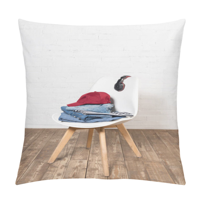 Personality  White Chair With Stacked Denim Clothes, Burgundy Cap And Wireless Headphones On Wooden Floor Near Brick Wall Pillow Covers