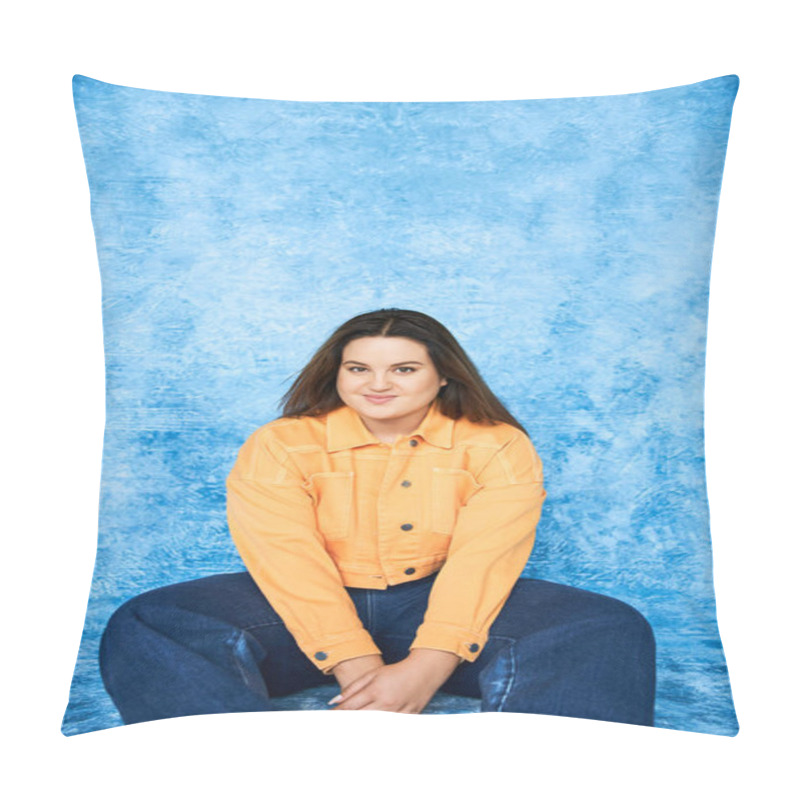 Personality  Body Positive, Plus Size Woman With Brunette Hair And Natural Makeup Sitting In Orange Jacket And Denim Jeans While Smiling And Looking At Camera On Mottled Blue Background  Pillow Covers