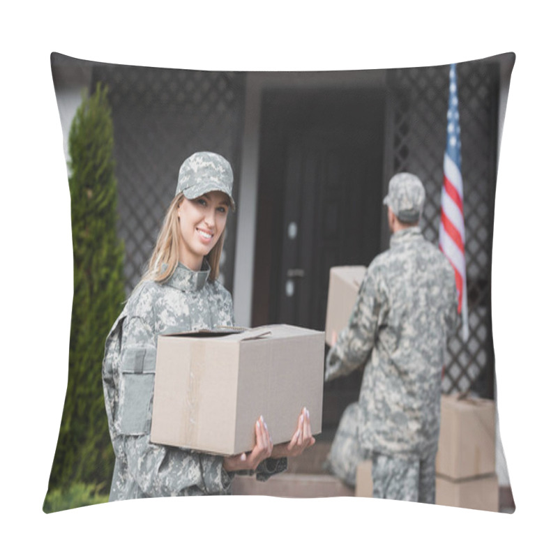 Personality  Smiling Woman In Camouflage Holding Cardboard Box And Looking At Camera With Blurred  Military Man On Background Pillow Covers