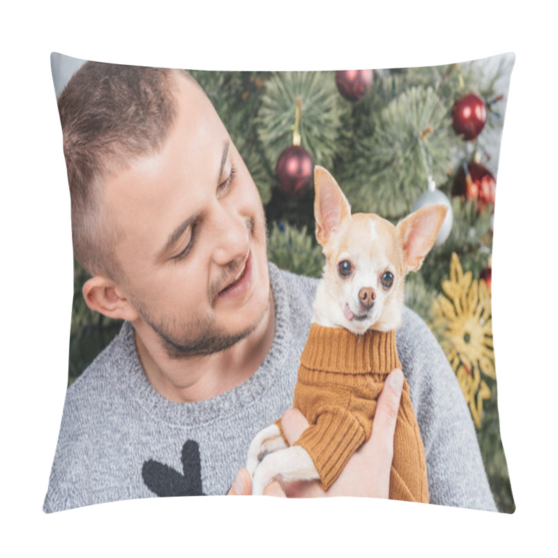 Personality  Portrait Of Young Man In Festive Winter Sweater Looking At Little Chihuahua Dog In Hands At Home Pillow Covers