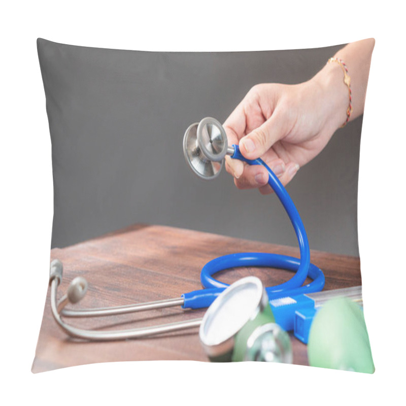 Personality  A Hand Holding A Stethoscope With Various Medical Instruments On A Wooden Table. The Stethoscope Has A Blue Tube And A Metallic Chest Piece, Alongside Other Medical Tools Like A Spectrophotometer. Pillow Covers