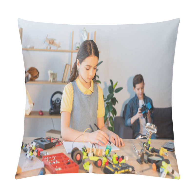 Personality  Preteen Girl Writing On Notebook Near Robotic Model And Blurred Friend At Home  Pillow Covers