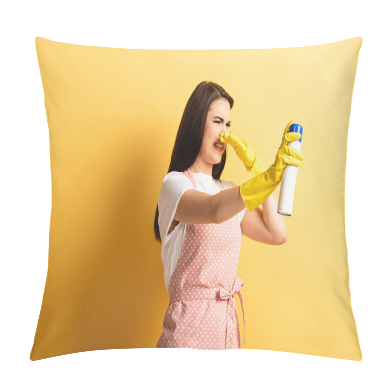 Personality  Displeased Housewife In Apron And Rubber Gloves Plugging Hose With Hand While Spraying Air Freshener On Yellow Background Pillow Covers