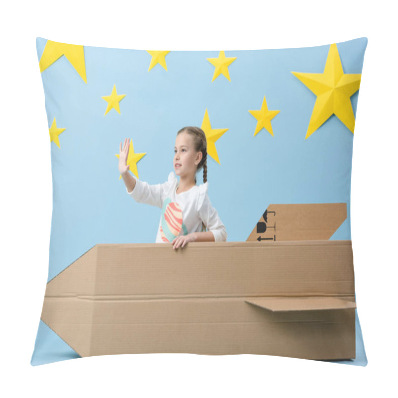 Personality  Kid With Braids Waving Hand While Sitting In Cardboard Rocket On Blue Starry Background Pillow Covers