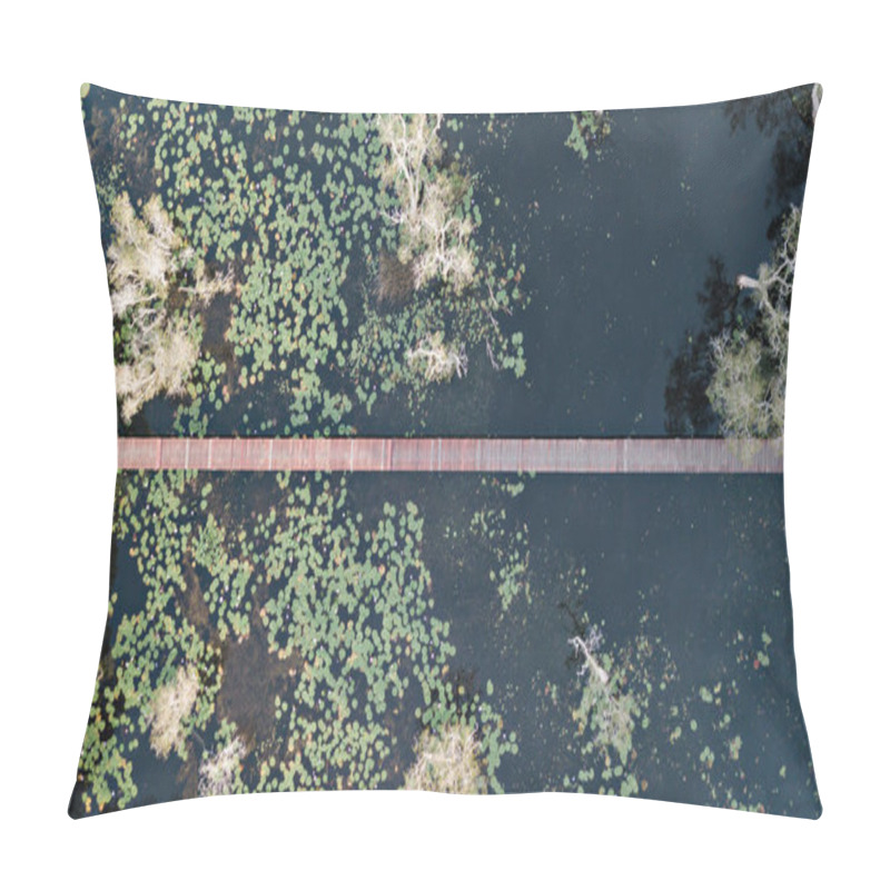 Personality  This Aerial Image Shows A Narrow Wooden Bridge Cutting Across A Calm, Dark Water Body Filled With Scattered Green Lily Pads. Surrounding The Water Are Clusters Of Pale Trees And Natural Vegetation. Pillow Covers