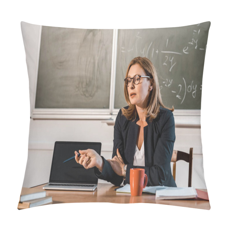 Personality  Female Teacher Sitting At Desk And Pointing At Laptop With Blank Screen In Classroom Pillow Covers