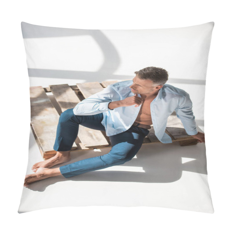 Personality  High Angle View Of Attractive Adult Man Sitting On Wooden Pallet On White And Looking Away Pillow Covers