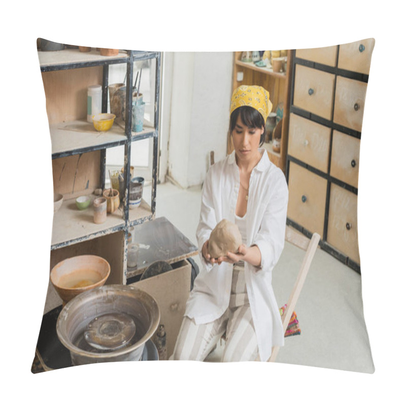 Personality  Young Brunette Asian Female Potter In Workwear And Headscarf Holding Clay Near Pottery Wheel While Working In Blurred Ceramic Workshop, Craftsmanship In Pottery Making Pillow Covers