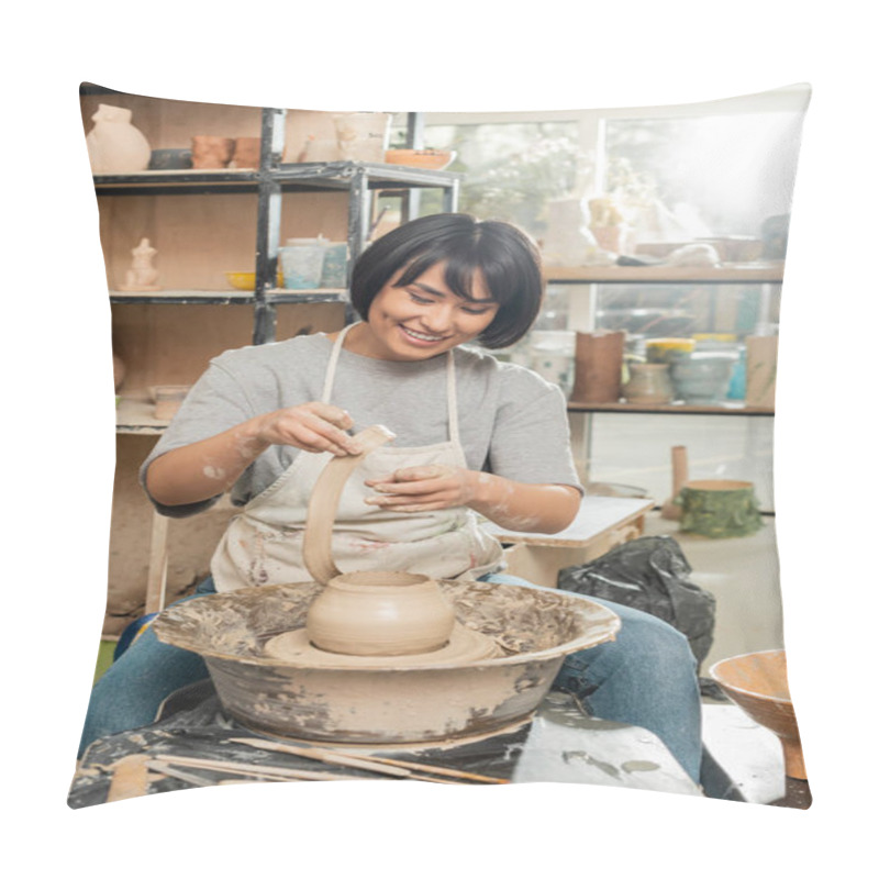 Personality  Cheerful Young Brunette Asian Artisan In Apron Holing Clay While Making Vase On Pottery Wheel Near Tools And Bowl In Blurred Ceramic Workshop, Artisanal Pottery Production And Process Pillow Covers