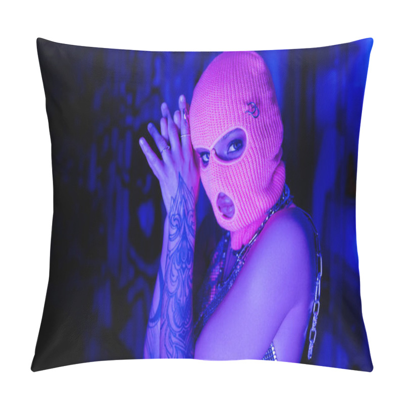 Personality  Young Tattooed Woman In Balaclava And Silver Neck Chains Looking At Camera Near Wall With Graffiti In Blue And Purple Light Pillow Covers