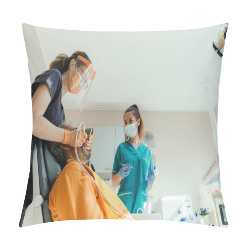 Personality  Low Angle View Of Male Patient Sitting On Dentist's Chair And Getting Dental Restoration By A Dentist With Assistance Of Female Dental Hygienist At Dental Clinic Pillow Covers