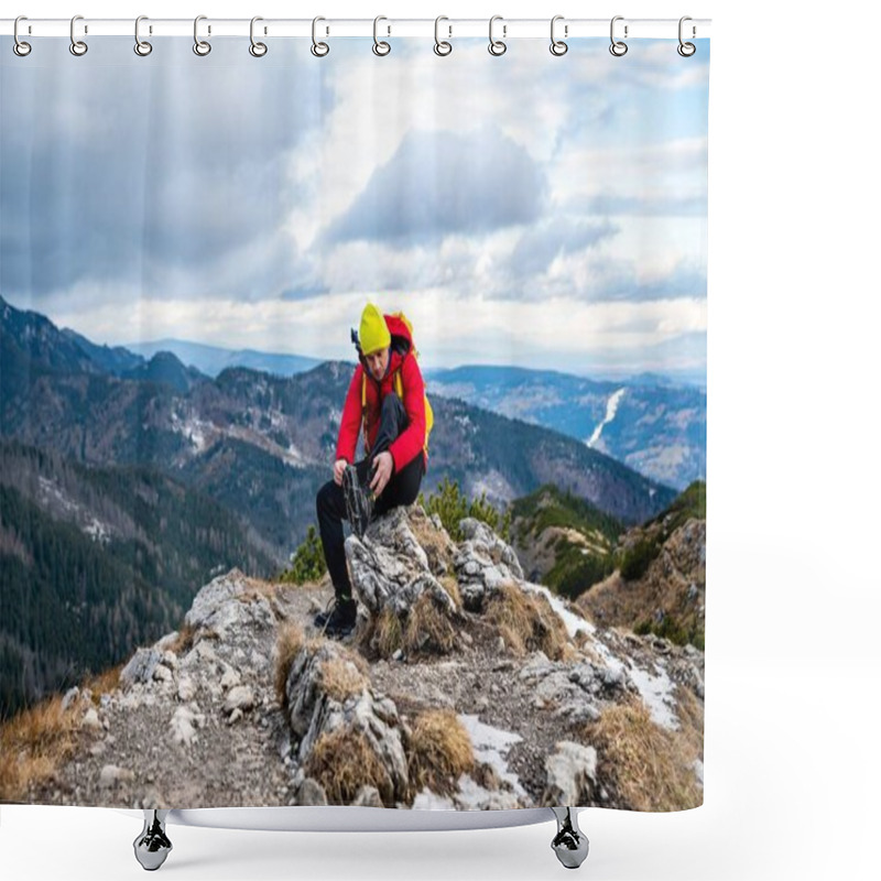 Personality  A Tourist In A Yellow Cap And A Red Down Jacket Sits On A Rock And Puts Crampons On His Shoes. Shower Curtains