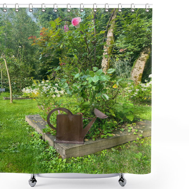 Personality  A Rusty Metal Watering Can Sculpture In A Flower Bed. The Piece Is Placed Next To A Lush Rose Bush With A Single Pink Bloom. Gardens Jardin Du Rossignol. Willeman, France Shower Curtains