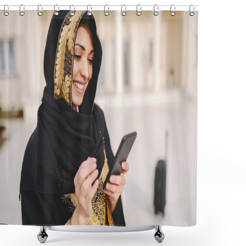 Personality  Portrait Of Charming Smiling Muslim Woman Dressed In Traditional Wear Using Smart Phone While Standing Outside. Shower Curtains