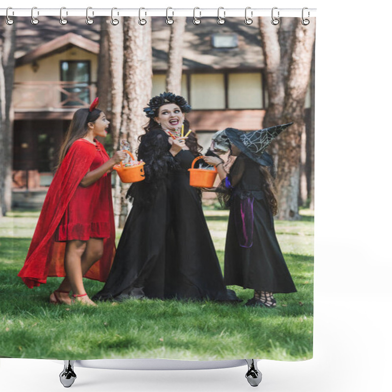 Personality  Astonished Woman With Daughters In Halloween Costumes Holding Buckets With Candies In Forest Near Blurred Cottage Shower Curtains