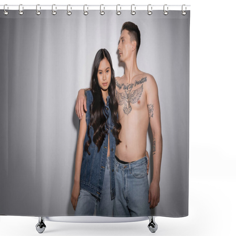 Personality  Brunette Asian Woman In Denim Vest And Jeans Looking At Camera Near Shirtless Tattooed Man On Grey Background Shower Curtains