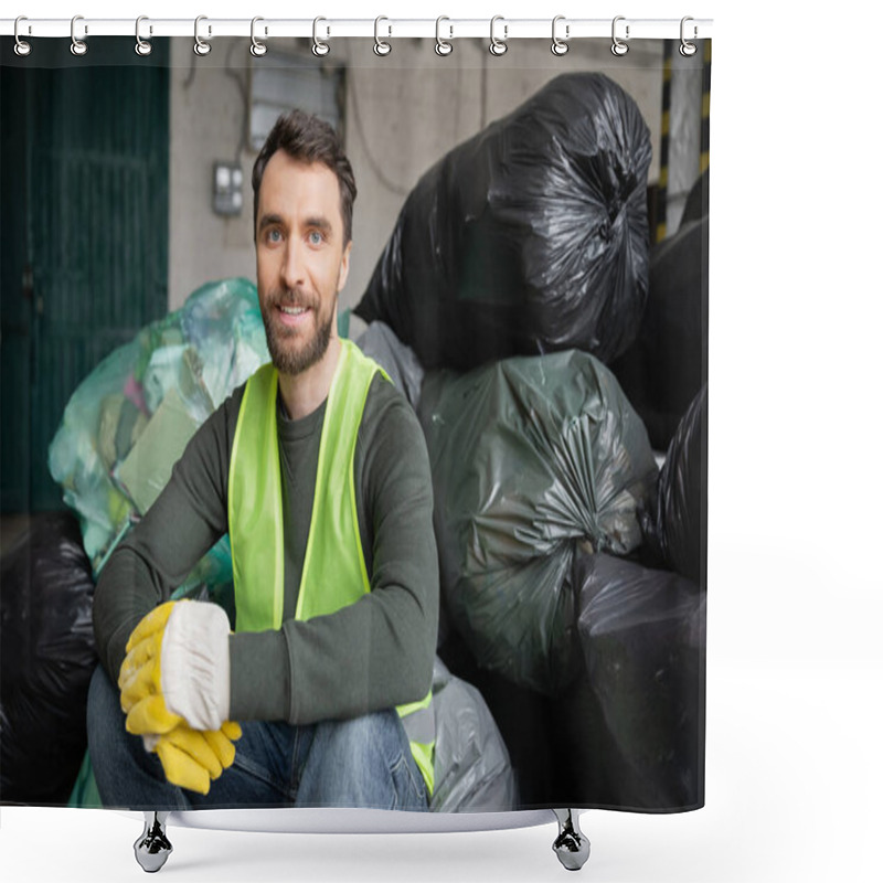 Personality  Smiling And Bearded Worker In Safety Vest And Gloves Looking At Camera While Sitting On Plastic Bags With Trash In Blurred Garbage Sorting Center, Recycling Concept Shower Curtains