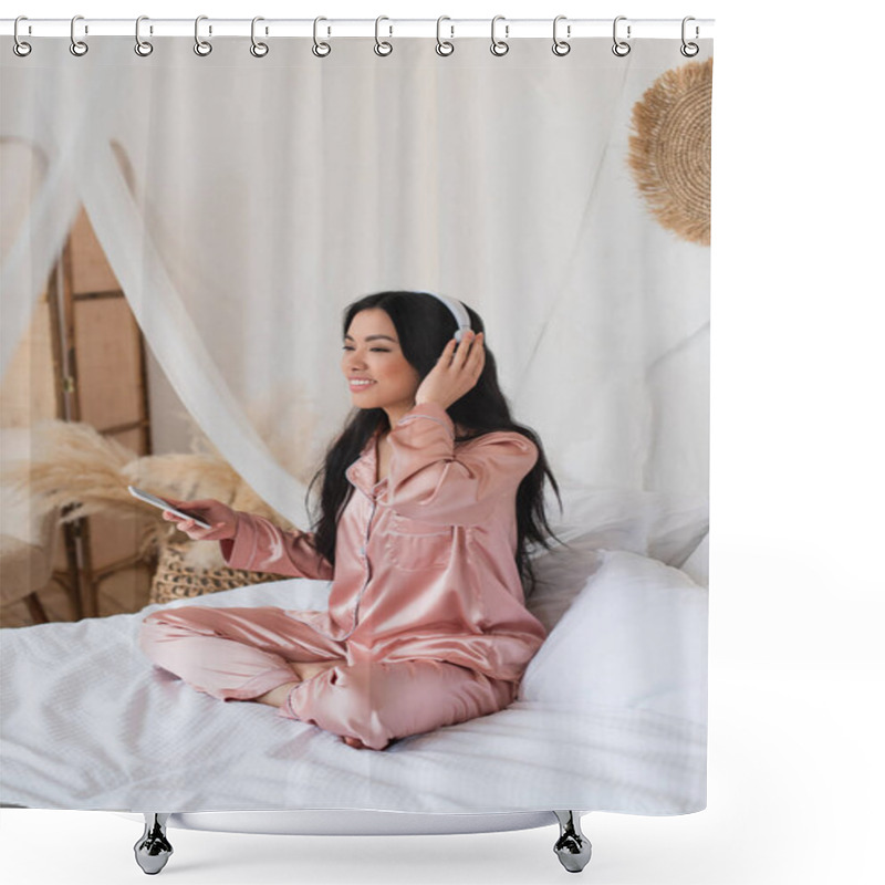 Personality  Young Asian Woman In Pink Silk Pajamas Sitting On Bed With Cellphone And Touching Headphones With Hand In Bedroom Shower Curtains