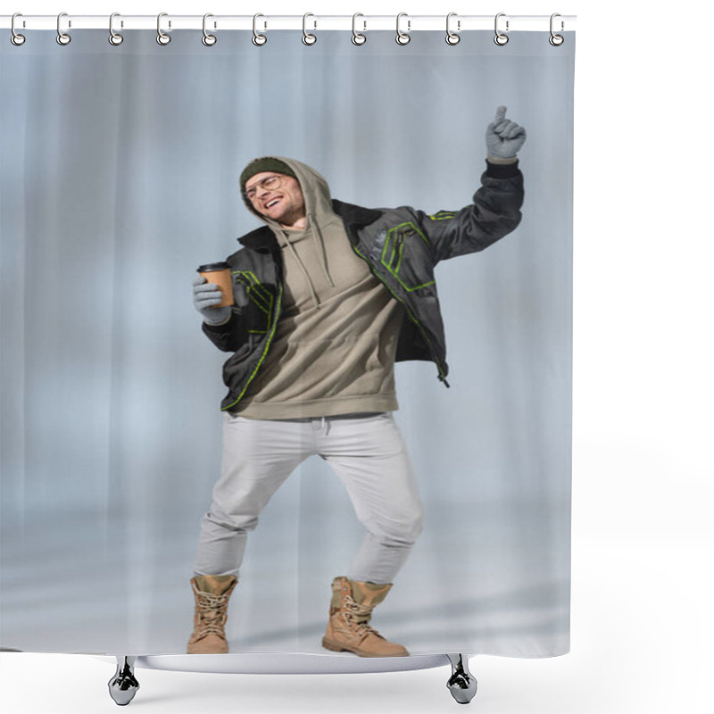 Personality  Full Length Of Young Happy Man In Hat, Hoodie And Anorak Holding Paper Cup And Dancing On Grey Shower Curtains