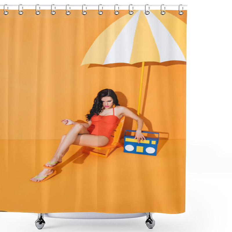 Personality  Young Woman In Swimsuit Touching Paper Boombox While Sitting On Deck Chair Near Umbrella On Orange Shower Curtains