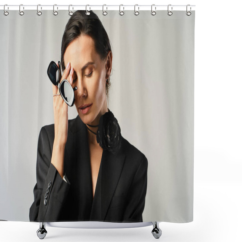 Personality  A Fashionable Woman In A Black Suit Confidently Holds A Pair Of Glasses Against A Grey Backdrop. Shower Curtains