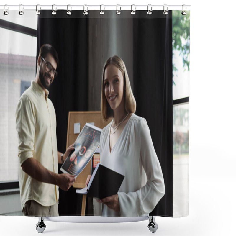 Personality  Smiling Intern Holding Notebook And Looking At Camera Near Businessman With Charts In Office  Shower Curtains