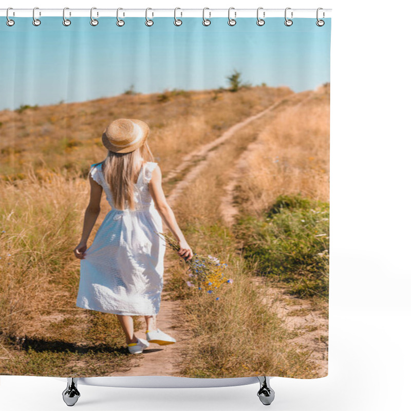 Personality  Back View Of Young Woman In White Dress And Straw Hat Holding Wildflowers While Walking On Road In Meadow Shower Curtains