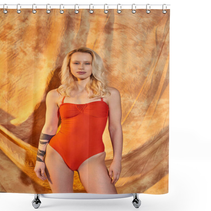 Personality  Stylish And Tattooed Blonde Woman In Orange Swimwear Posing On Beige Backdrop With Drapery Shower Curtains