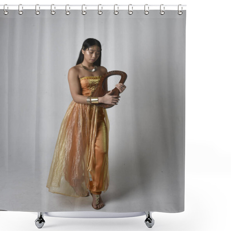 Personality  Full Length Portrait Of Pretty Young Asian Woman Wearing Golden Arabian Robes Like A Genie, Holding A Small Musical Harp, Isolated On Studio Background. Shower Curtains