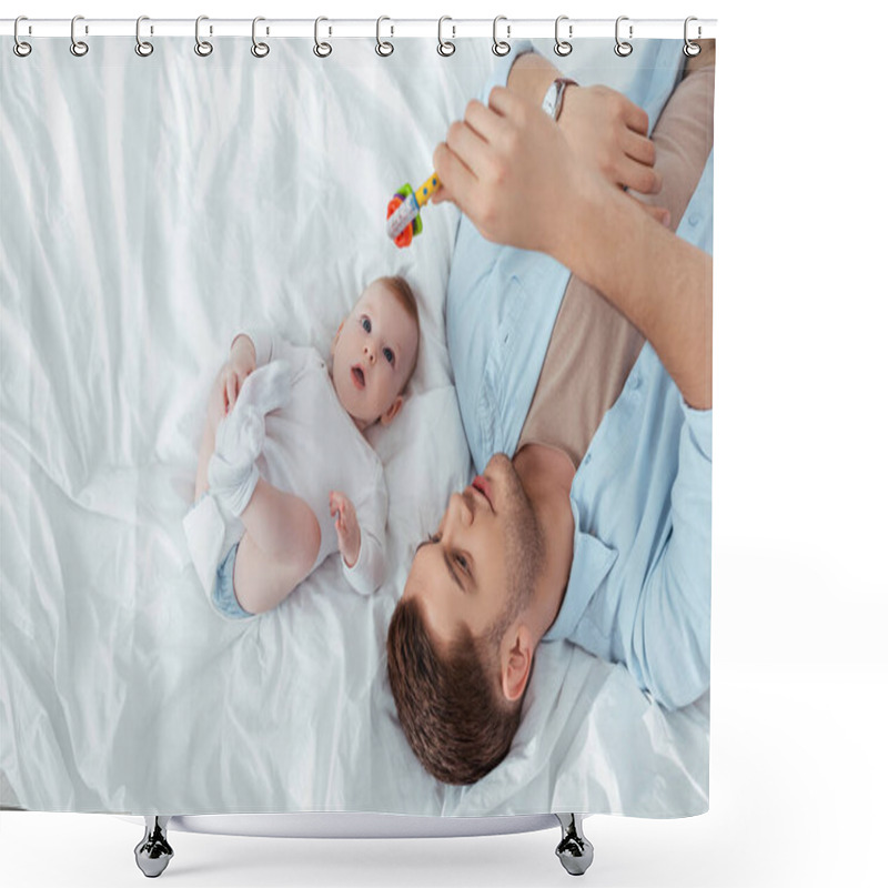 Personality  Top View Of Young Father Playing With Baby Rattle Over Cute Little Son Lying In Bed Shower Curtains