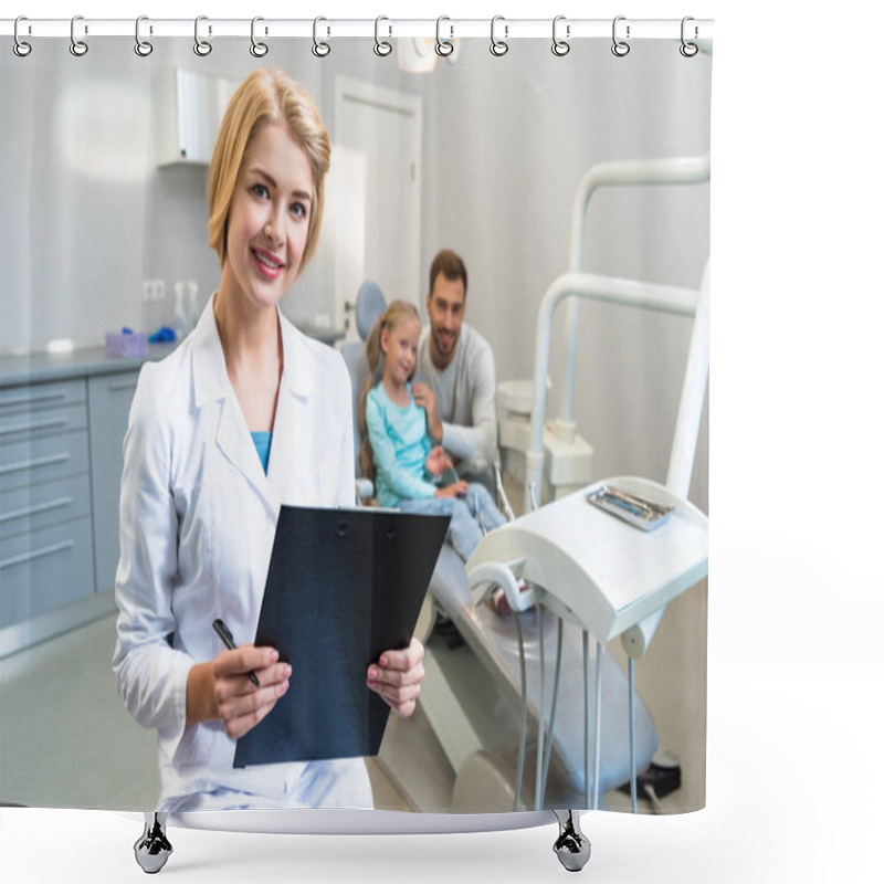 Personality  Beautiful Female Dentist With Clipboard Looking At Camera While Little Child And Her Father Sitting On Background Shower Curtains