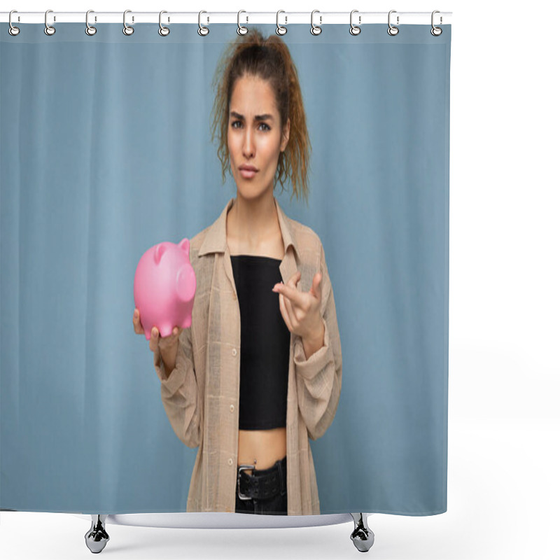 Personality  Portrait Photo Of Sincere Emotional Dissatisfied Young Beautiful Woman With Dark Curly Hair In A Ponytail Wearing Casual Beige Shirt Isolated Over Blue Background With Empty Space And Holds Pink Pig Shower Curtains