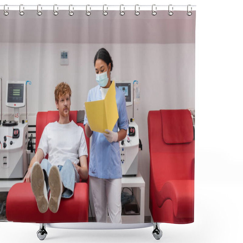 Personality  Multiracial Healthcare Worker In Uniform And Medical Mask Showing Paper Folder To Redhead Volunteer Sitting On Medical Chair Near Transfusion Machine In Laboratory Shower Curtains