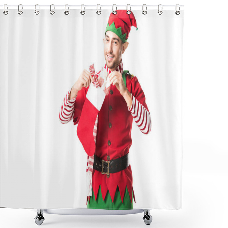 Personality  Smiling Man In Christmas Elf Costume Putting Present In Red Christmas Stocking And Looking At Camera Isolated On White Shower Curtains