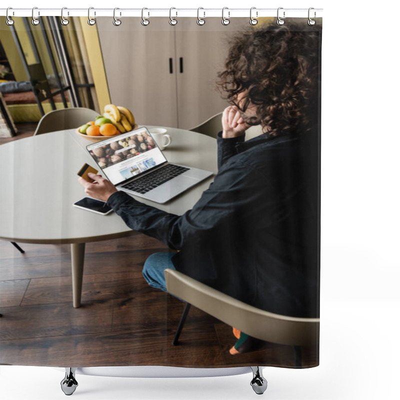 Personality  KYIV, UKRAINE - APRIL 25, 2020: Back View Of Freelancer Holding Credit Card While Sitting At Laptop With Depositphotos On Screen, Smartphone And Fruits Shower Curtains