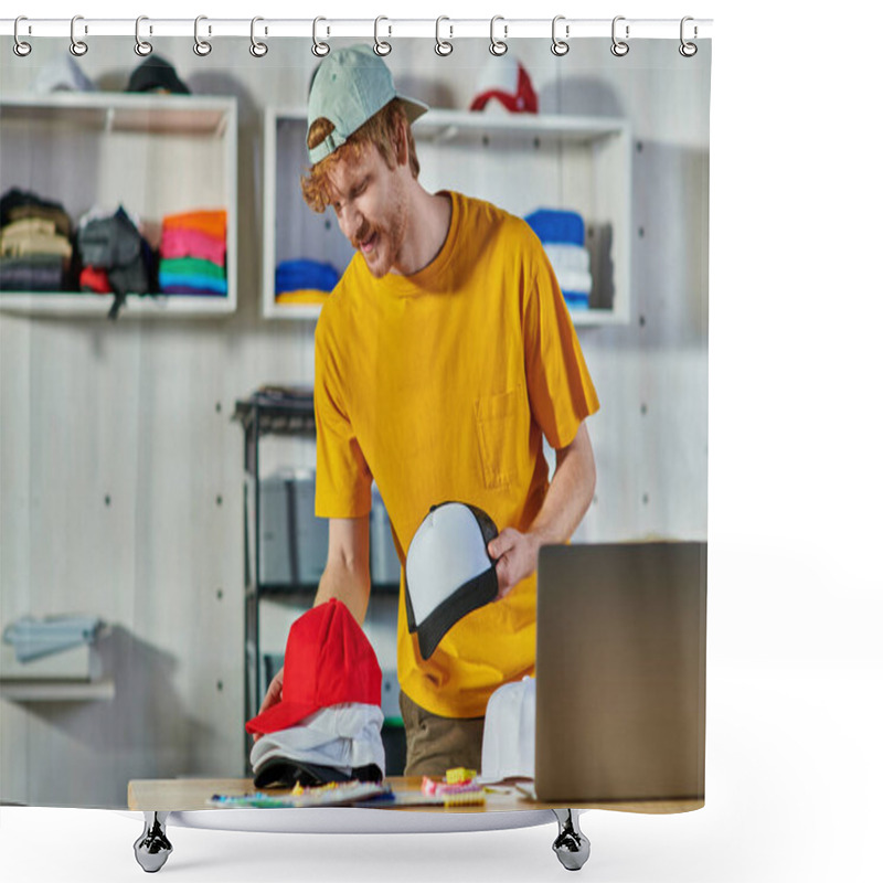 Personality  Cheerful Young Redhead Craftsman Holding Snapbacks While Working Near Cloth Samples And Blurred Laptop On Wooden Table In Print Studio, Small Business Resilience Concept Shower Curtains