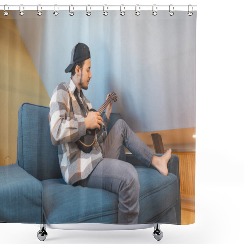 Personality  Man With Talent Sits On A Gray Sofa, Carefully Tuning A Black Ukulele. Musician Is Enjoying The Feeling Of Playing The Ukulele And Immersing Oneself In The Creative Spirit. Shower Curtains