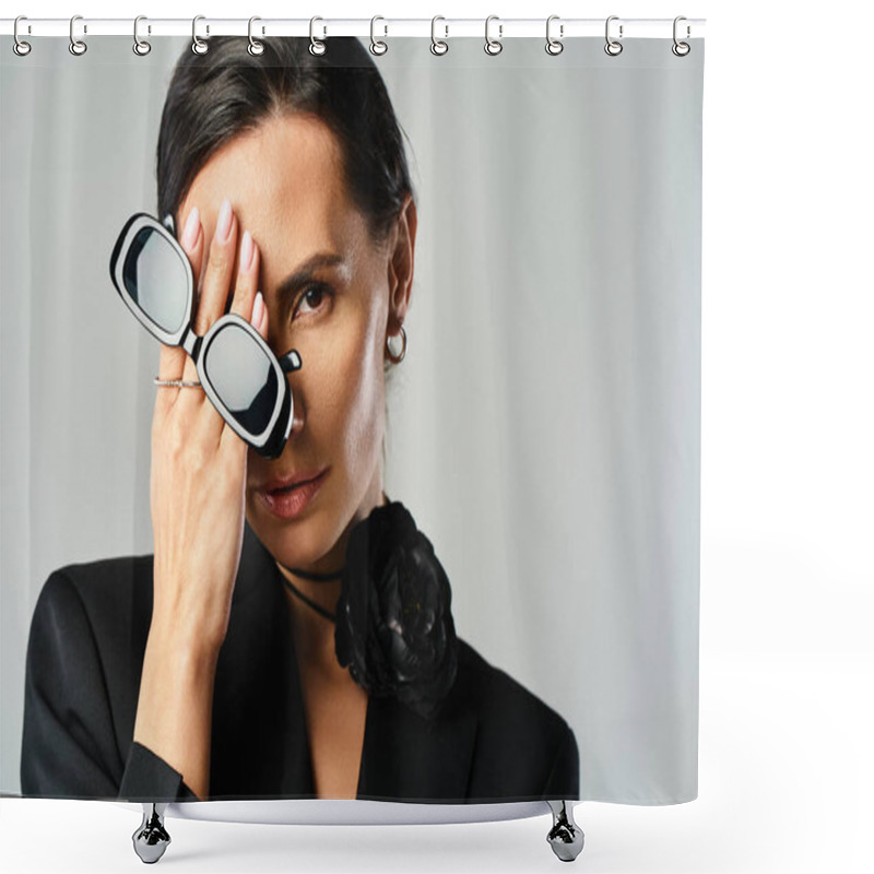 Personality  A Stylish Woman In A Black Suit Confidently Holds A Pair Of Glasses In A Studio Setting With A Grey Background. Shower Curtains