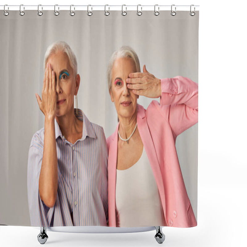 Personality  Trendy Mature Models In Blue And Pink Wear Obscuring Faces With Hands And Looking At Camera On Grey Shower Curtains