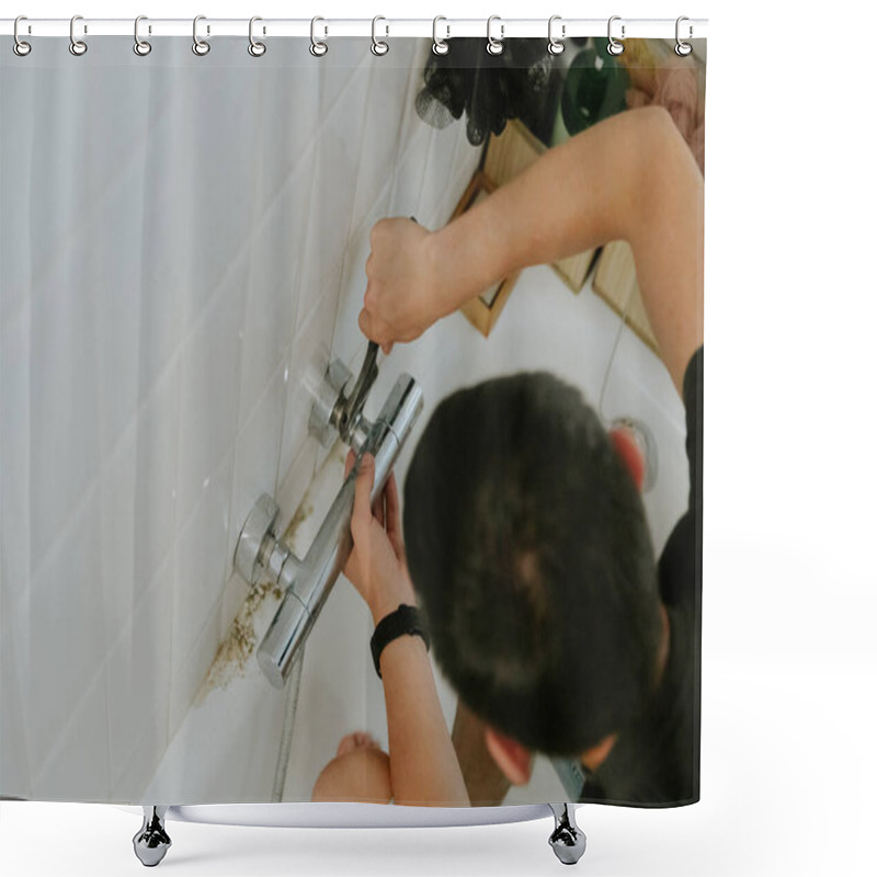 Personality  One Young Caucasian Brunette Man Manually Tightens The Nut On The Faucet In The Wall Using An Adjustable Wrench While Sitting On The Edge Of The Bathtub, Top View. Step By Step. Shower Curtains