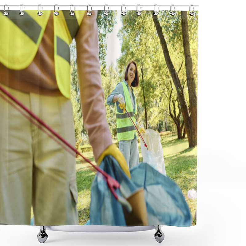 Personality  A Woman In A Yellow Safety Vest Is Holding A Blue Bag While Volunteering In A Park Cleanup With Her Partner. Shower Curtains