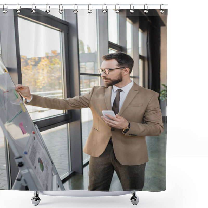 Personality  Serious Manager In Stylish Formal Wear And Eyeglasses Holding Smartphone And Sticky Note Near Flip Chart With Graphs While Thinking About Business Strategy In Office Shower Curtains