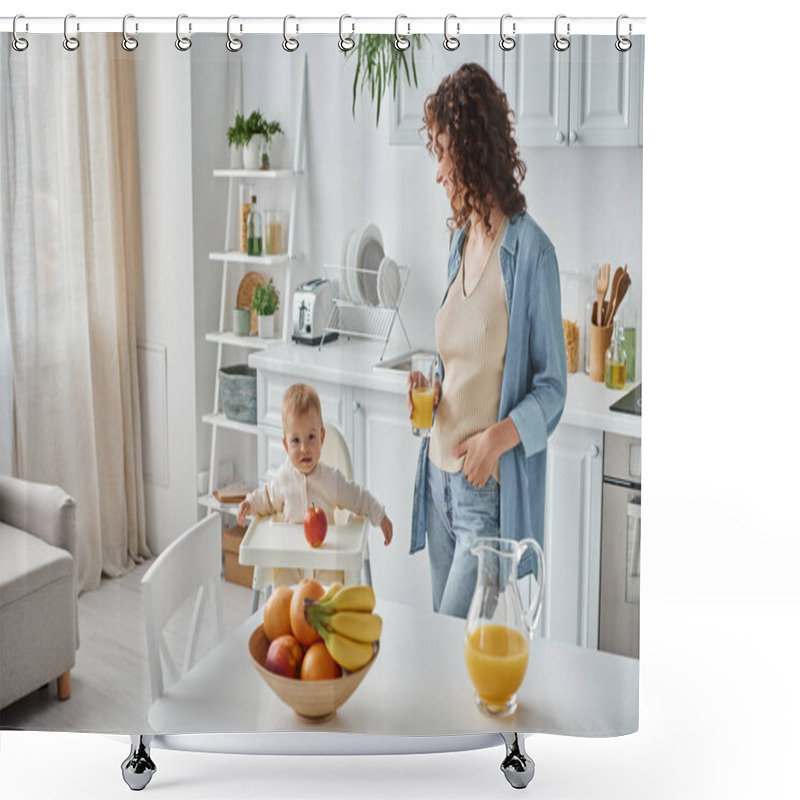 Personality  Curly Woman With Glass Of Orange Juice Looking At Child In Baby Chair In Kitchen With Ripe Fruits Shower Curtains