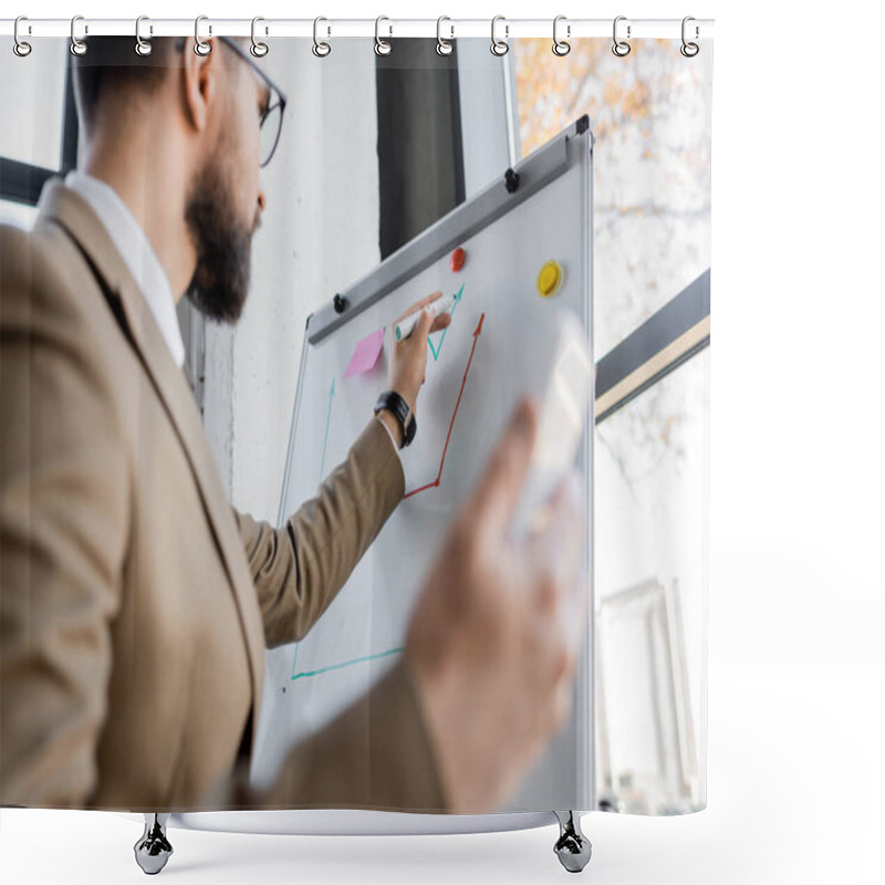 Personality  Low Angle View Of Bearded Businessman In Beige Blazer Holding Blurred Smartphone And Drawing Graphs On Flip Chart While Making Business Analytics In Office Shower Curtains