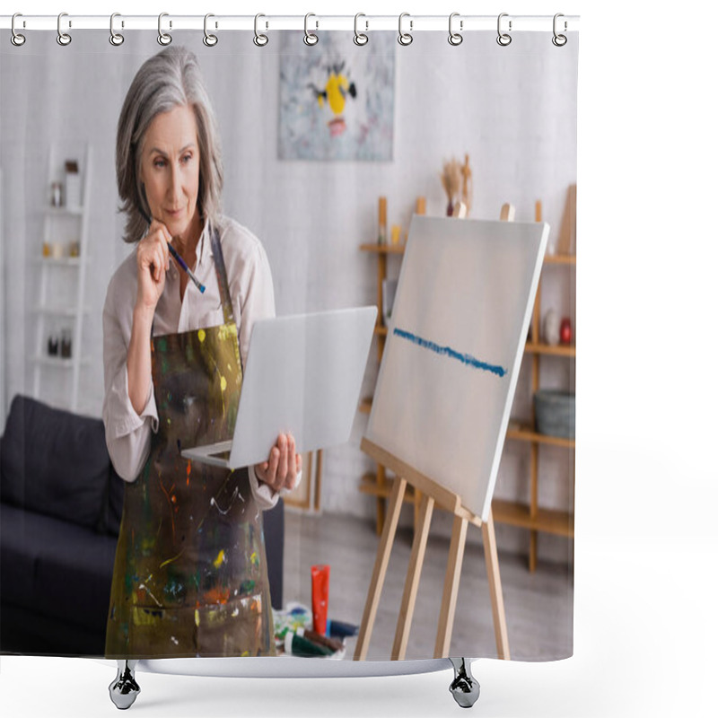 Personality  Mature Woman Holding Paintbrush And Laptop While Watching Tutorial Near Canvas Shower Curtains