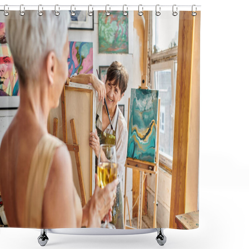 Personality  Cheerful Mature Woman Artist Looking At Blurred Female Model Posing With Wine Glass In Workshop Shower Curtains